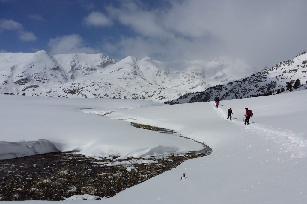Paysage hivernal dans le massif du Néouvielle avec un groupe de randonneurs en raquettes avec leur guide dans la neige