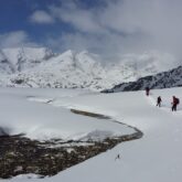 Paysage hivernal dans le massif du Néouvielle avec un groupe de randonneurs en raquettes avec leur guide dans la neige
