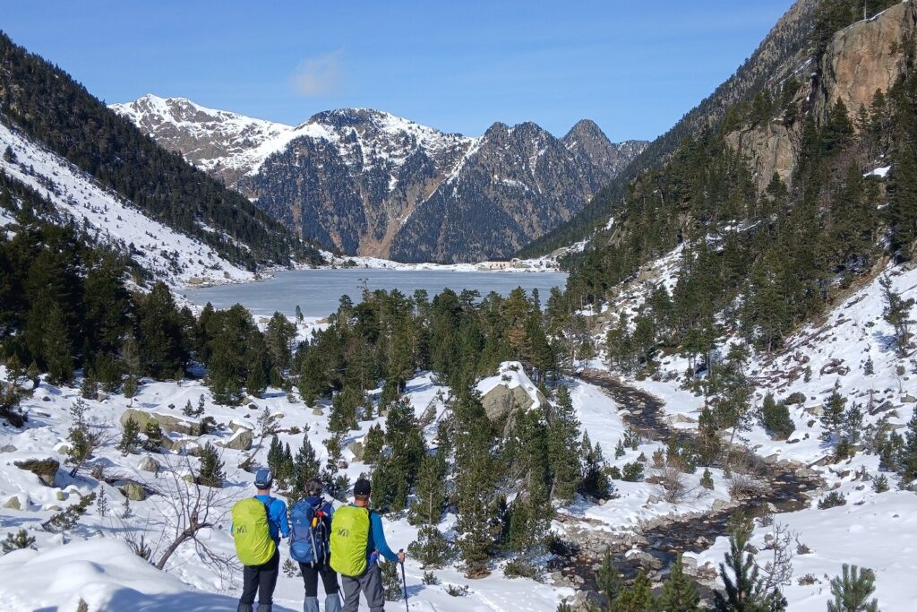 Groupe de randonneurs avec leur guide face à la vue d'un des acs du Néouville gelé au cours de l'hiver lors d'une randonnée en raquettes