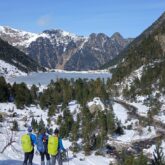 Groupe de randonneurs avec leur guide face à la vue d'un des acs du Néouville gelé au cours de l'hiver lors d'une randonnée en raquettes