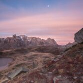 Paysage dans la zone de la commune de Névache au petit matin avec des couleurs rosées dans le ciel et un lac de montagne sur la droite