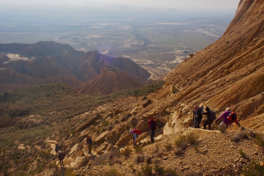 Paysage d'une vallée dans les Bardenas avec un groupe de randonneurs sur un sentier qui descend