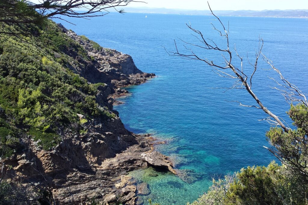 Paysage de littoral avec de l'eau turquoise en contrebas et des rochers de part et d'autre d'une petite crique