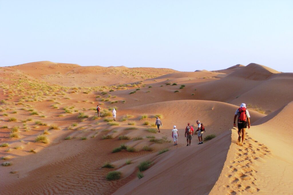 Groupe de randonneurs à Oman sur un sentier à travers les dunes avec leur guide