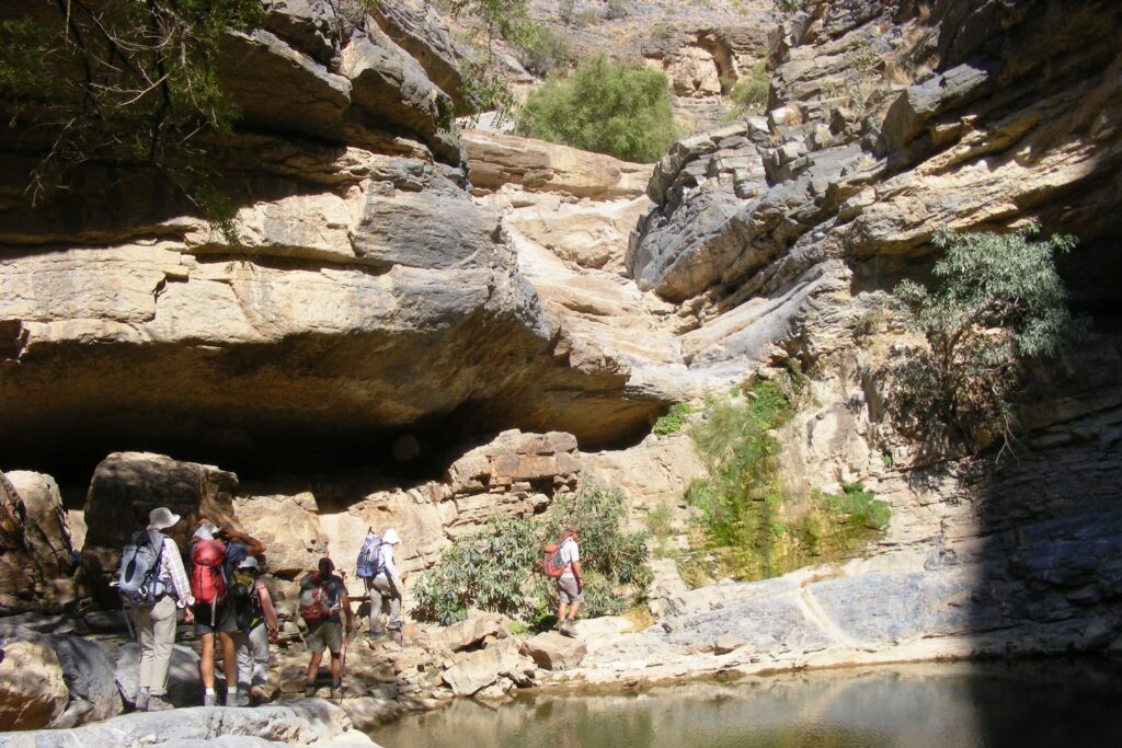 Groupe de randonneurs sur un sentier de randonnée avec leur guide, le sentier est bordé d'un point d'eau