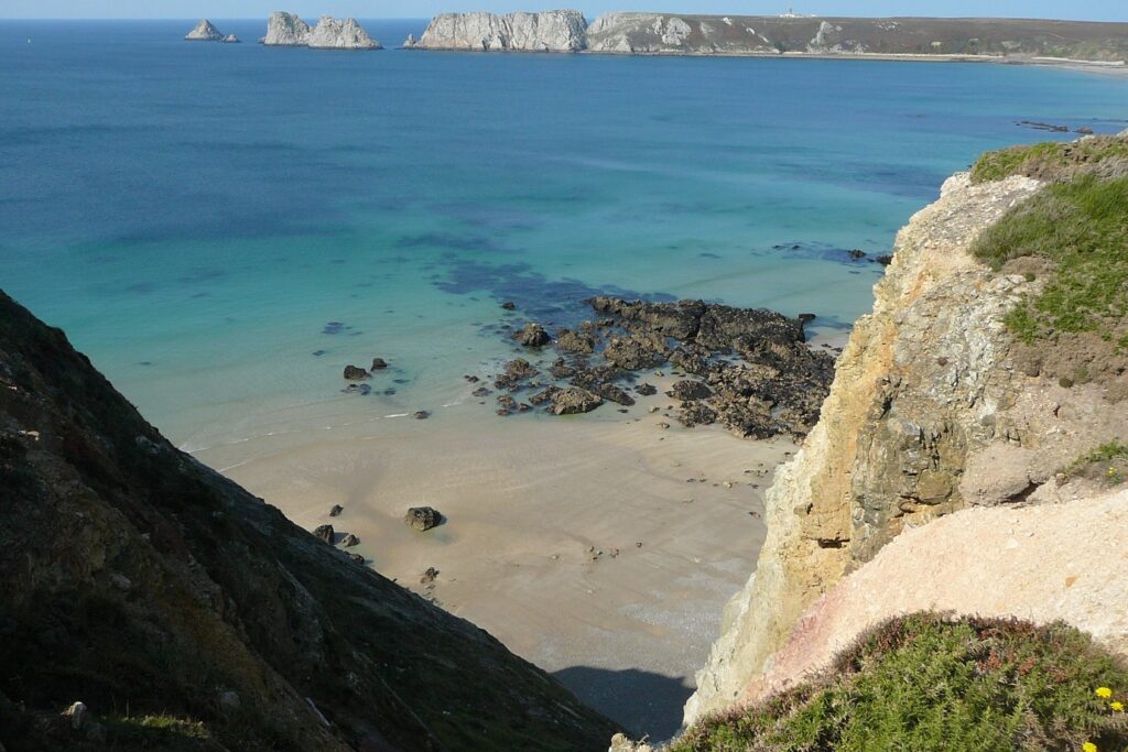 Paysage côtier avec l'eau turquoise sur une plage de sable surplombée par des rochers