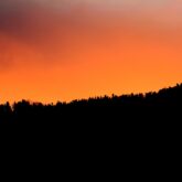 Paysage au coucher du soleil avec des couleurs orangées à contrejour de la montagne