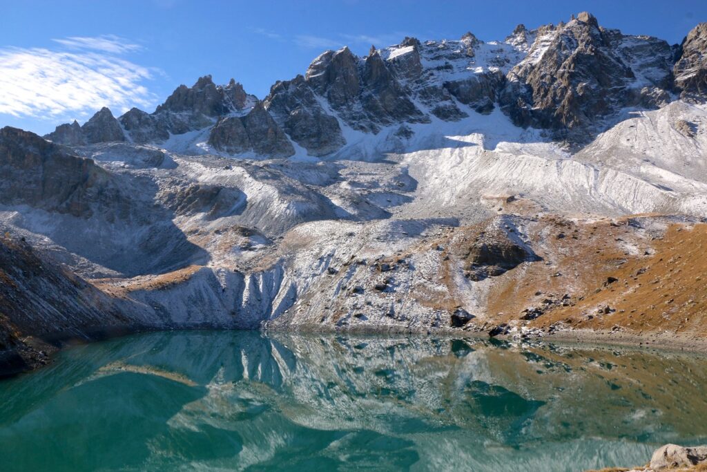 Paysage dans le Queyras avec un lac au premier plan et des sommets couverts de neige et de glace à l'arrière-plan