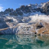Paysage dans le Queyras avec un lac au premier plan et des sommets couverts de neige et de glace à l'arrière-plan