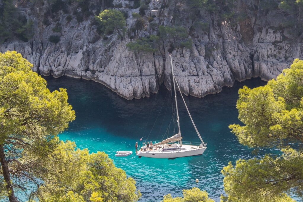 Prise de vue en hauteur de l'eau turquoise avec un bateau, encadré de falaises et d'arbres