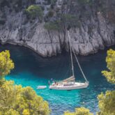Prise de vue en hauteur de l'eau turquoise avec un bateau, encadré de falaises et d'arbres