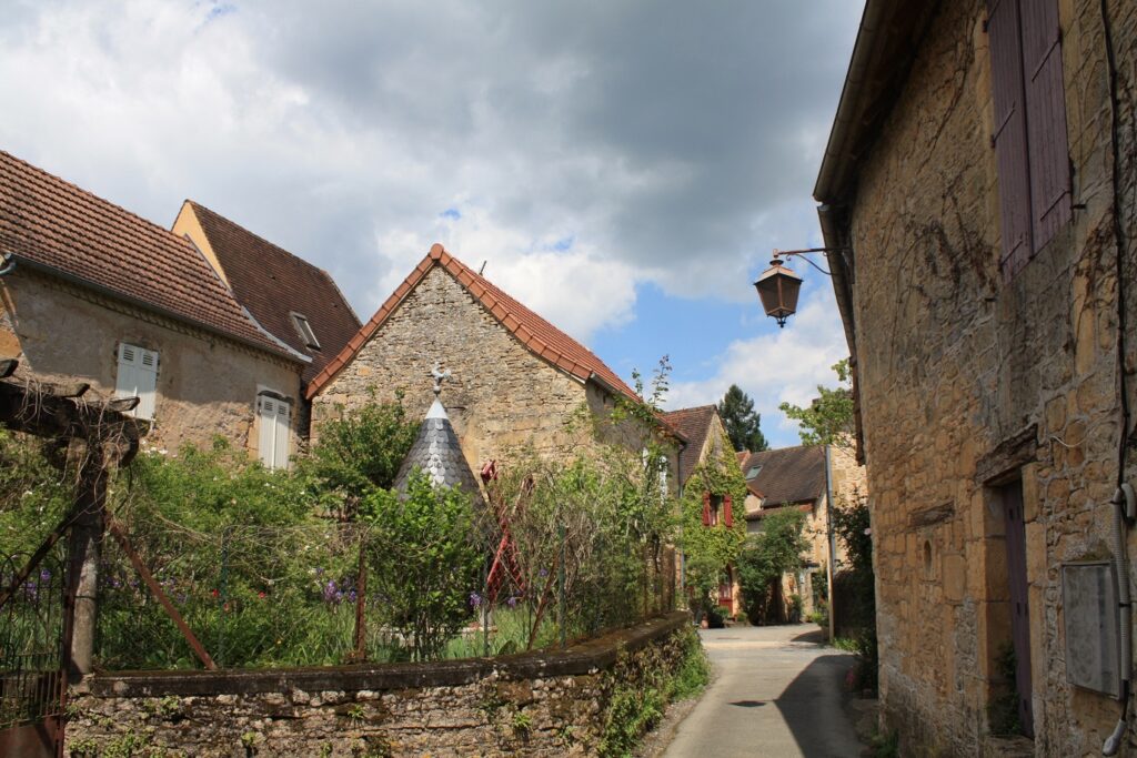 Paysage de randonnée dans un village de Dordogne avec des maisons caractéristiques de part et d'autre de la rue