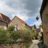 Paysage de randonnée dans un village de Dordogne avec des maisons caractéristiques de part et d'autre de la rue