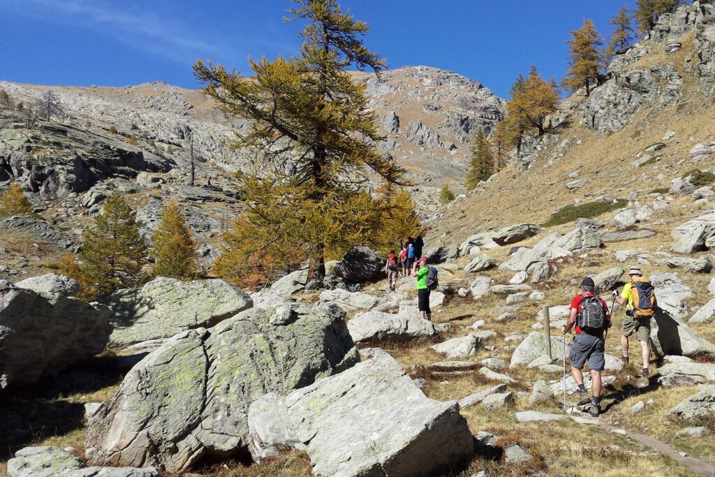 chemin rocailleux à travers la montagne, on y voit un groupe de randonneurs accompagné de leur guide en train de monter