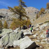 chemin rocailleux à travers la montagne, on y voit un groupe de randonneurs accompagné de leur guide en train de monter