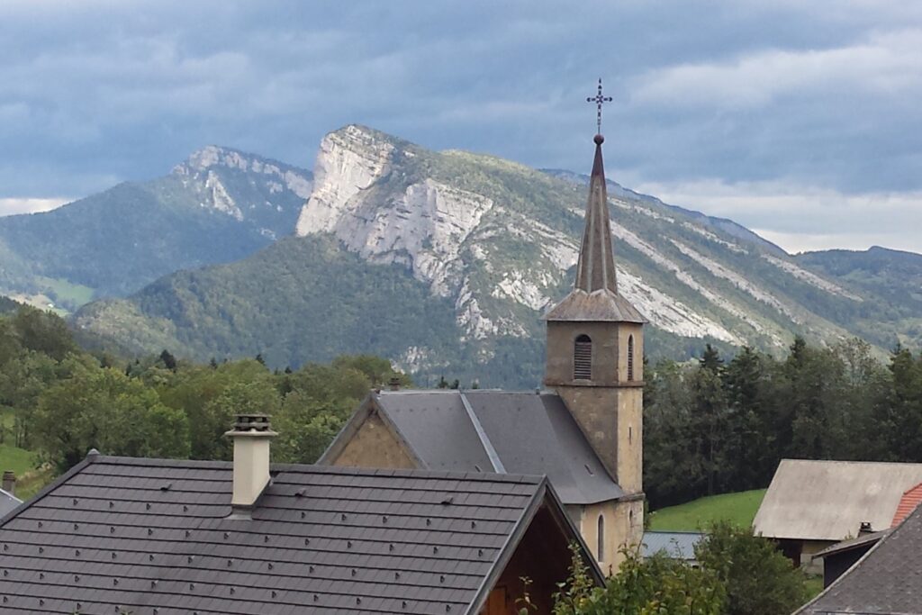 Paysage d'un village avec l'église en contrebas et des sommets à l'arrière-plan