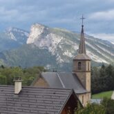 Paysage d'un village avec l'église en contrebas et des sommets à l'arrière-plan