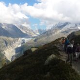 Paysage montagnard observé par des randonneurs et leur guide au cours d'une randonnée du tour du mont Blanc nord.