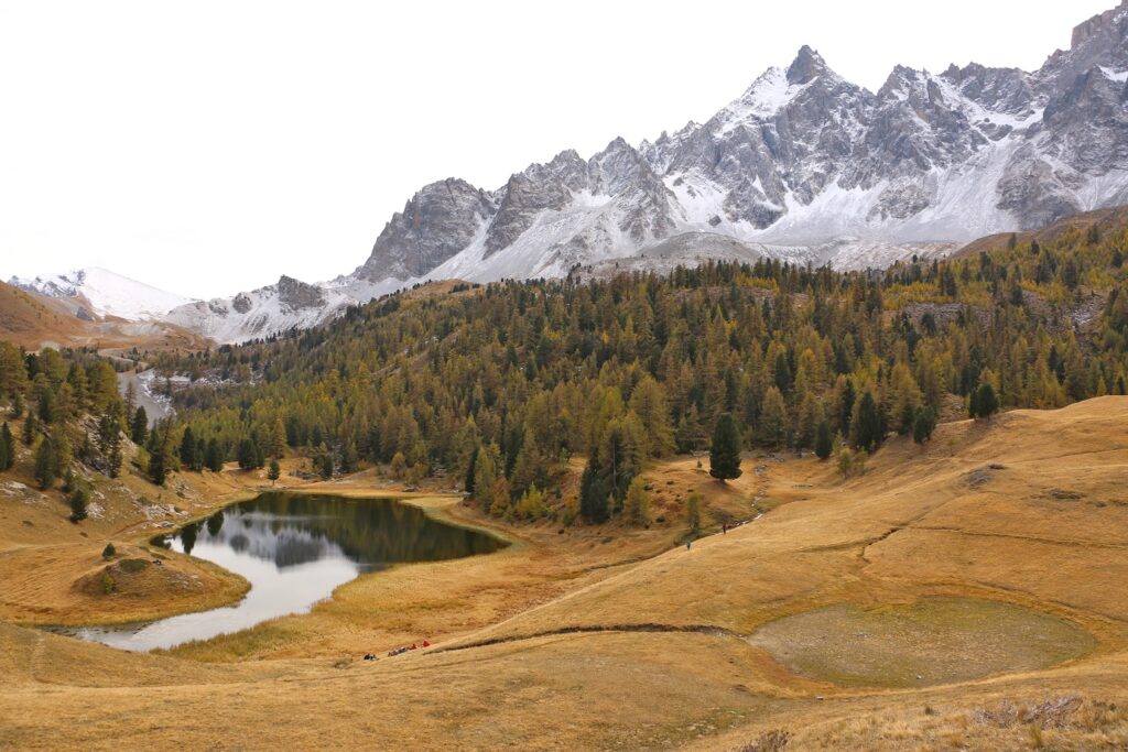 Paysage de montagne dans le domaine du Queyras avec un lac de montagne en contrebas et des sommets enneigés à l'arrière-plan
