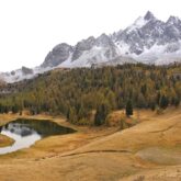 Paysage de montagne dans le domaine du Queyras avec un lac de montagne en contrebas et des sommets enneigés à l'arrière-plan