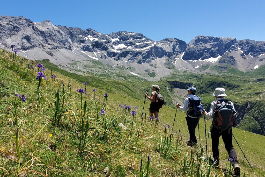 Paysage de montagne avec en fond une crête de montagne et au premier plan un groupe de randonneurs sur un sentier à flanc de montagne