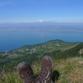 Photo d'un marcheur assis dans l'herbe au sommet d'une montagne avec le lac Léman en contrebas