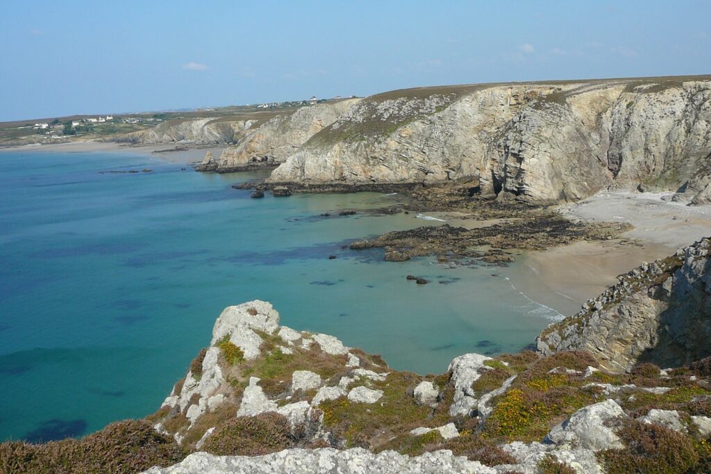 Paysage de bord d'océan avec de l'eau turquoise devant des plages de sable surplombées de falaises