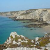 Paysage de bord d'océan avec de l'eau turquoise devant des plages de sable surplombées de falaises