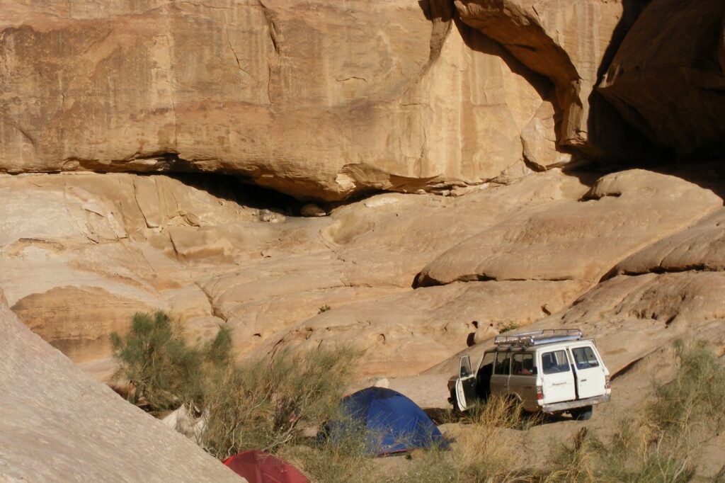 Paysage d'un campement en Jordanie avec des tentes et une voiture adaptée aux conditions, encadré de sommets de pierre