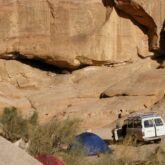 Paysage d'un campement en Jordanie avec des tentes et une voiture adaptée aux conditions, encadré de sommets de pierre