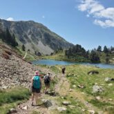Groupe de randonneurs sur un sentier qui se dirigent vers un lac de montagne