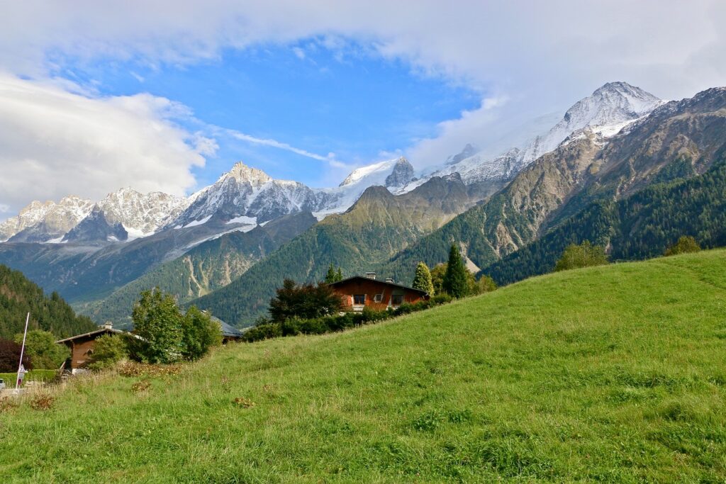 Paysage montagnard avec des sommets en fond et un chalet en bois au premier plan