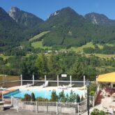 Paysage de montagne avec au premier plan la piscine de l'hôtel ainsi que la terrasse de ce dernier, et à l'arrière-plan on y voit différents sommets