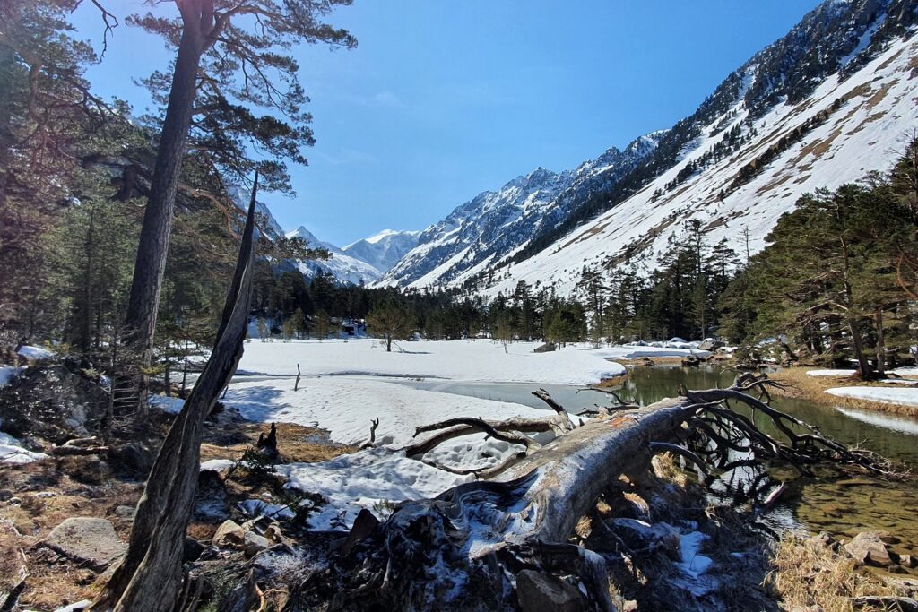 Paysage enneigé aux abords d'un la de montagne dans le massif du Néouvielle encadré de sommets et de paysages hivernaux