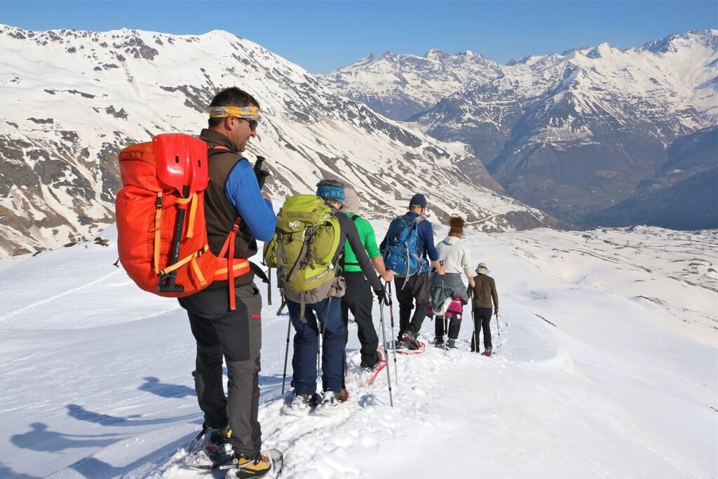 Groupe de randonneurs sur un sentier avec leur guide, en face d'eaux des sommets des hautes Pyrénées