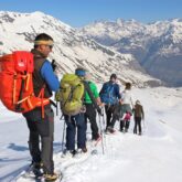 Groupe de randonneurs sur un sentier avec leur guide, en face d'eaux des sommets des hautes Pyrénées