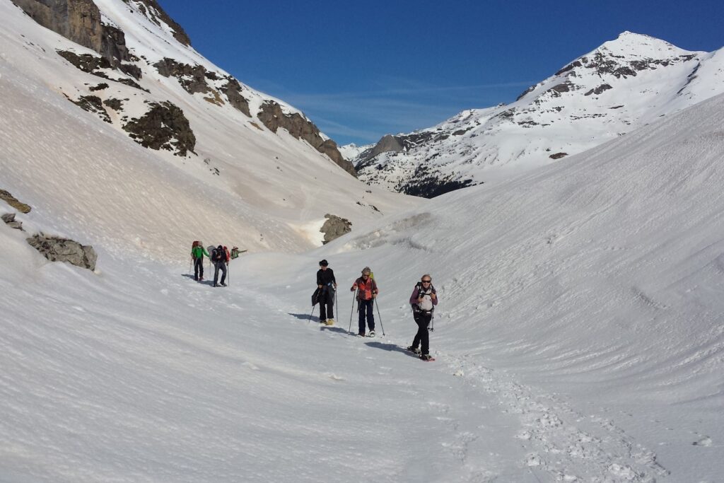 Groupe de randonneurs en raquettes avec leur guide sur un sentier dans un vallon d'une montagne entre Gavarnie et Cauterets