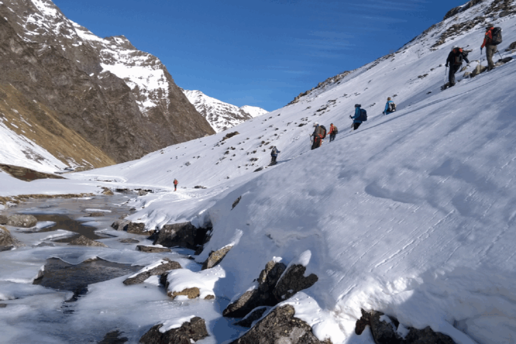 Groupe de randonneurs à flanc de montagne en train de descendre vers un cours d'eau