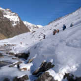 Groupe de randonneurs à flanc de montagne en train de descendre vers un cours d'eau