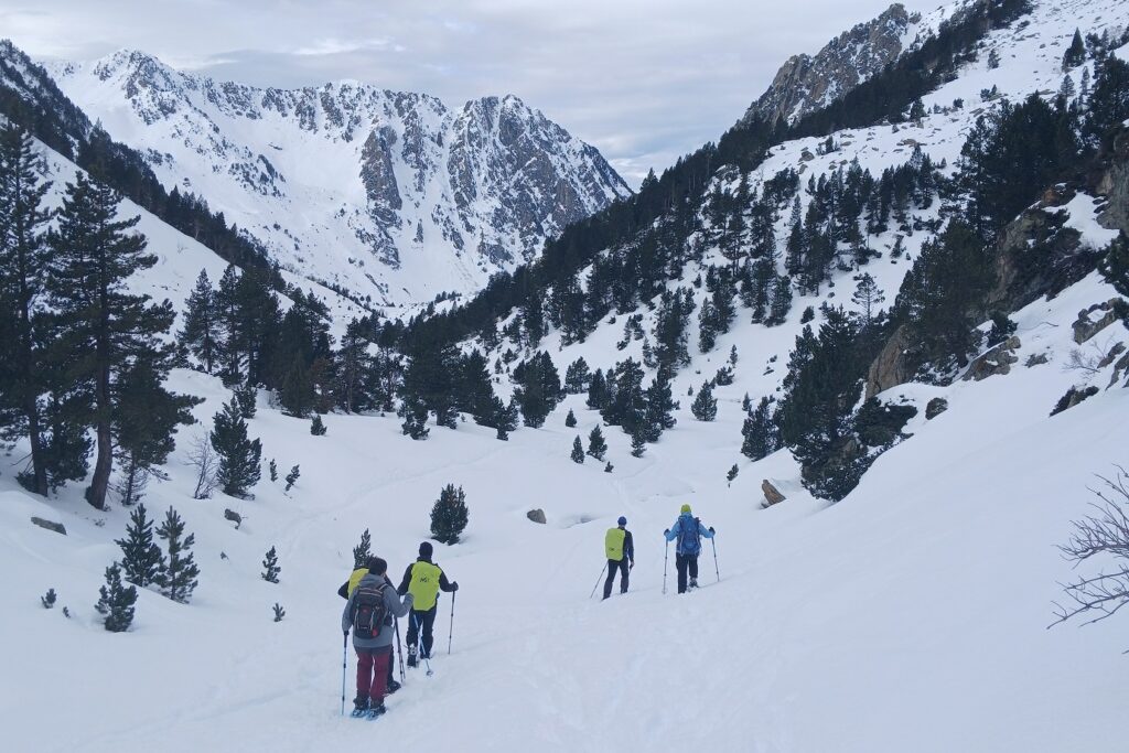 Groupe de randonneurs avec leur guide sur un sentier de randonnée entre Cauterets et le Néouvielle, le paysage est enneigé avec en fond des sommets