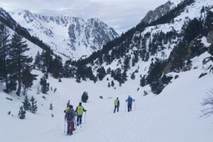 Groupe de randonneurs avec leur guide sur un sentier de randonnée entre Cauterets et le Néouvielle, le paysage est enneigé avec en fond des sommets