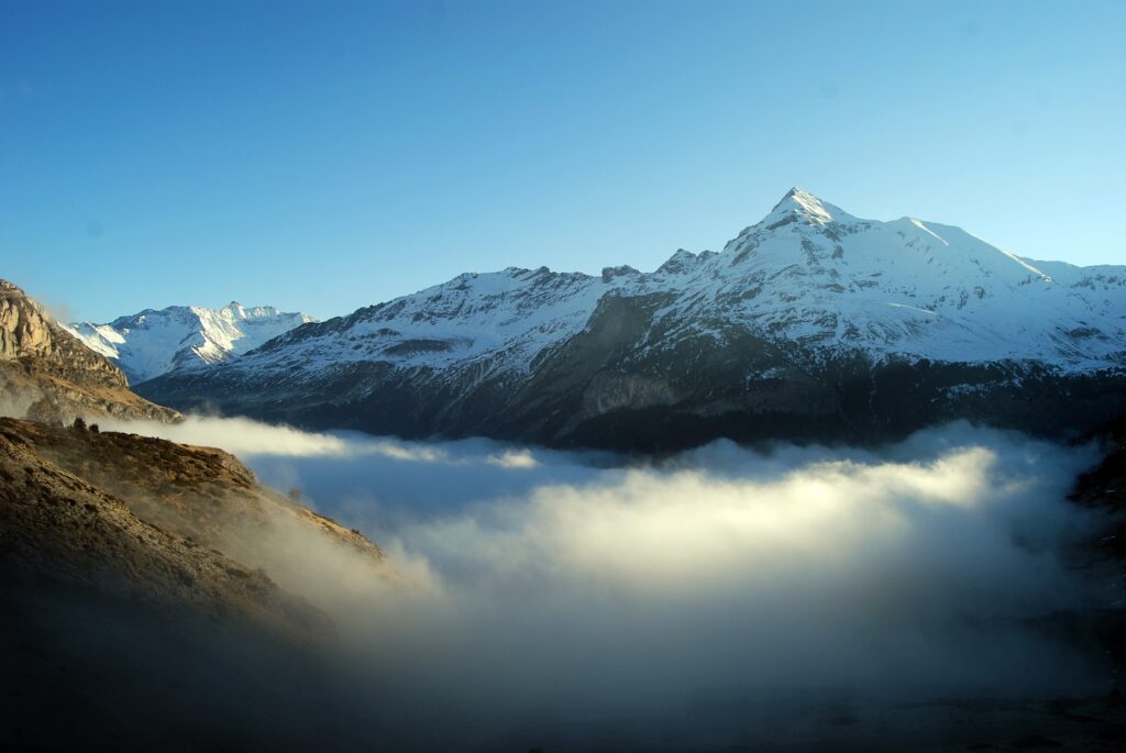 Paysage de montagne avec des sommets à l'arrière-plan et des nuages en contrebas.
