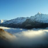 Paysage de montagne avec des sommets à l'arrière-plan et des nuages en contrebas.