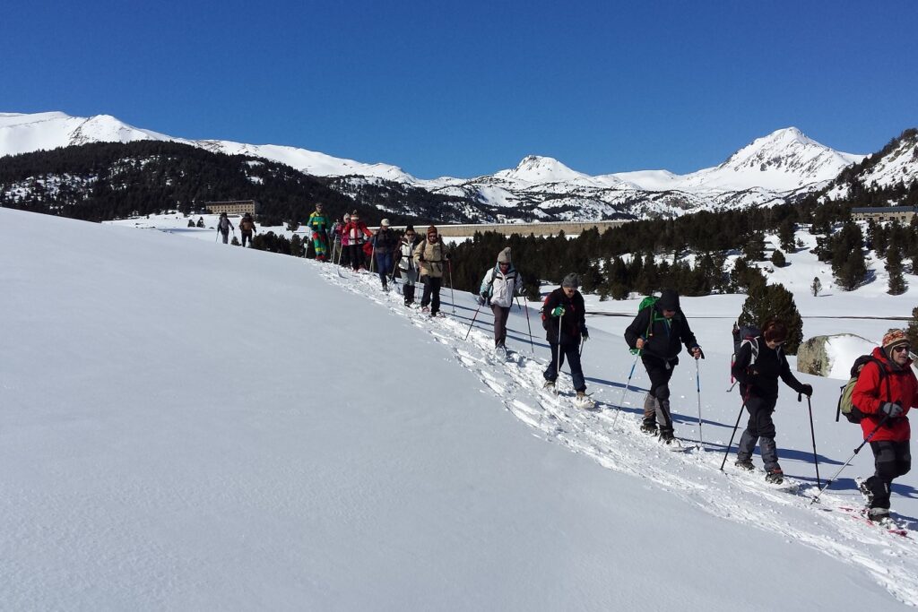 Groupe de randonneurs sur un sentier de randonnée en raquettes avec leur guide dans les Pyrénées orientales, au cours d'un séjour pour réveillon au refuge des Bouillouses