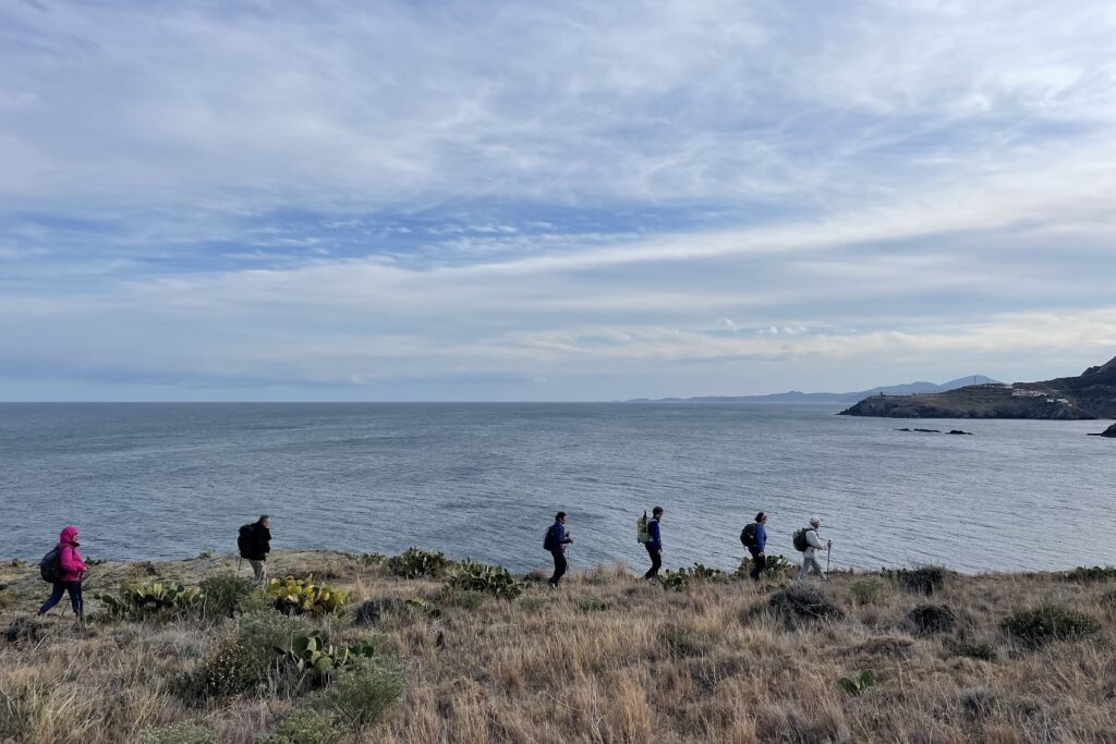 Groupe de randonneurs sur un sentier de randonnée avec la mer en arrière plan