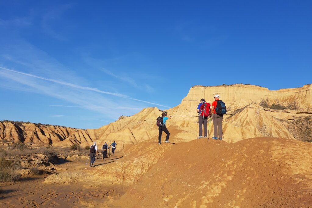 Groupe de randonneurs sur un sentier dans le désert des Bardenas en Espagne, entouré de reliefs caractéristiques notamment de par leur couleur ocre