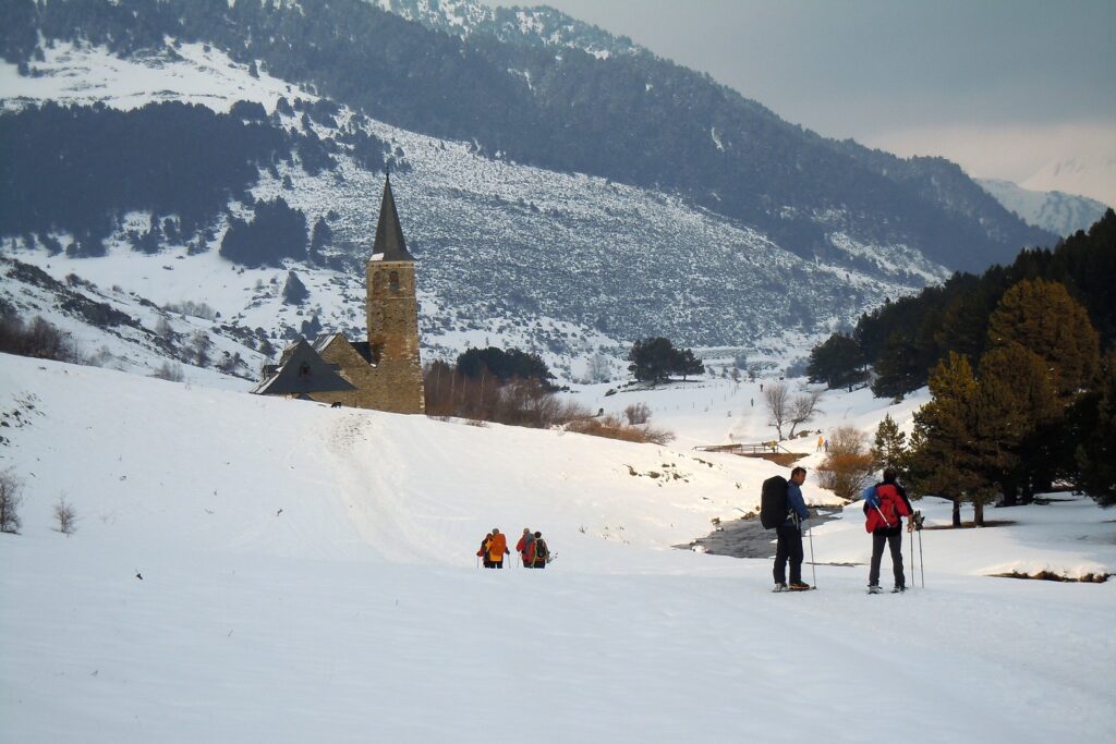 Groupe de randonneurs en raquettes avec leur guide sur un sentier de randonnée face au sanctuaire de Montgarri