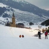 Groupe de randonneurs en raquettes avec leur guide sur un sentier de randonnée face au sanctuaire de Montgarri
