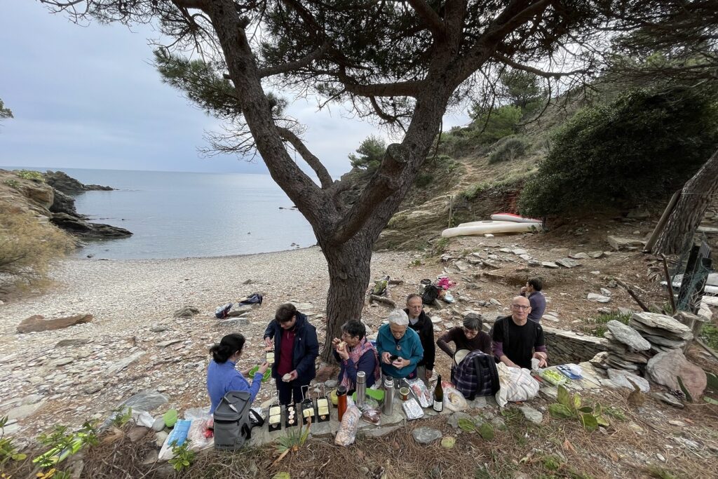 Groupe de randonneurs en bord de mer avec leur guide lors d'un pique-nique raclette au bord de l'eau