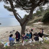 Groupe de randonneurs en bord de mer avec leur guide lors d'un pique-nique raclette au bord de l'eau